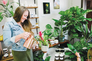 Leilani Zehnder, who grew up on Kauai, waters a bromeliad at Botanic and Luxe. PHOTO: KEANA PARKER